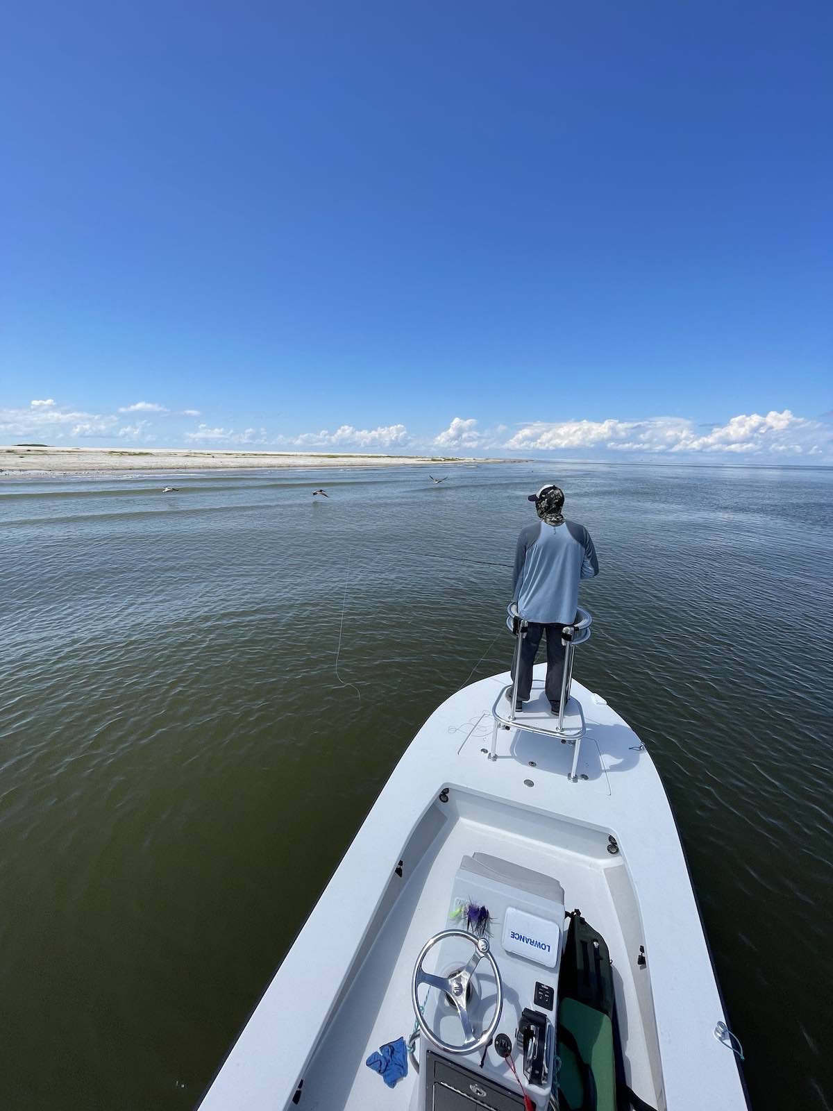 Standing on bow of skiff scanning water for fish